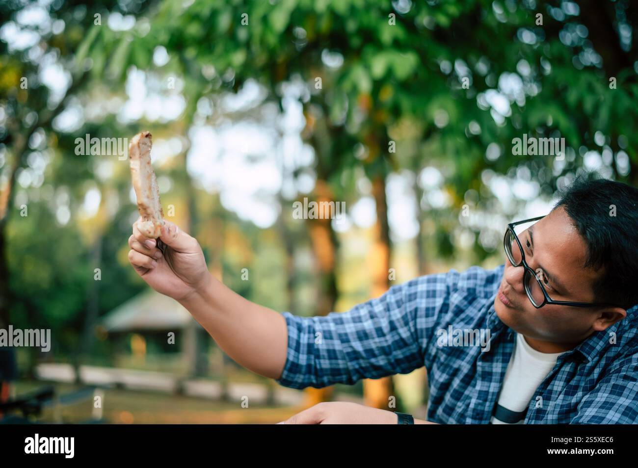 Ritratto dell'uomo viaggiatore asiatico che prepara una bistecca di maiale, barbecue in padella arrostita o pentola in campeggio. Cucina all'aperto, viaggi, campeggio, Foto Stock