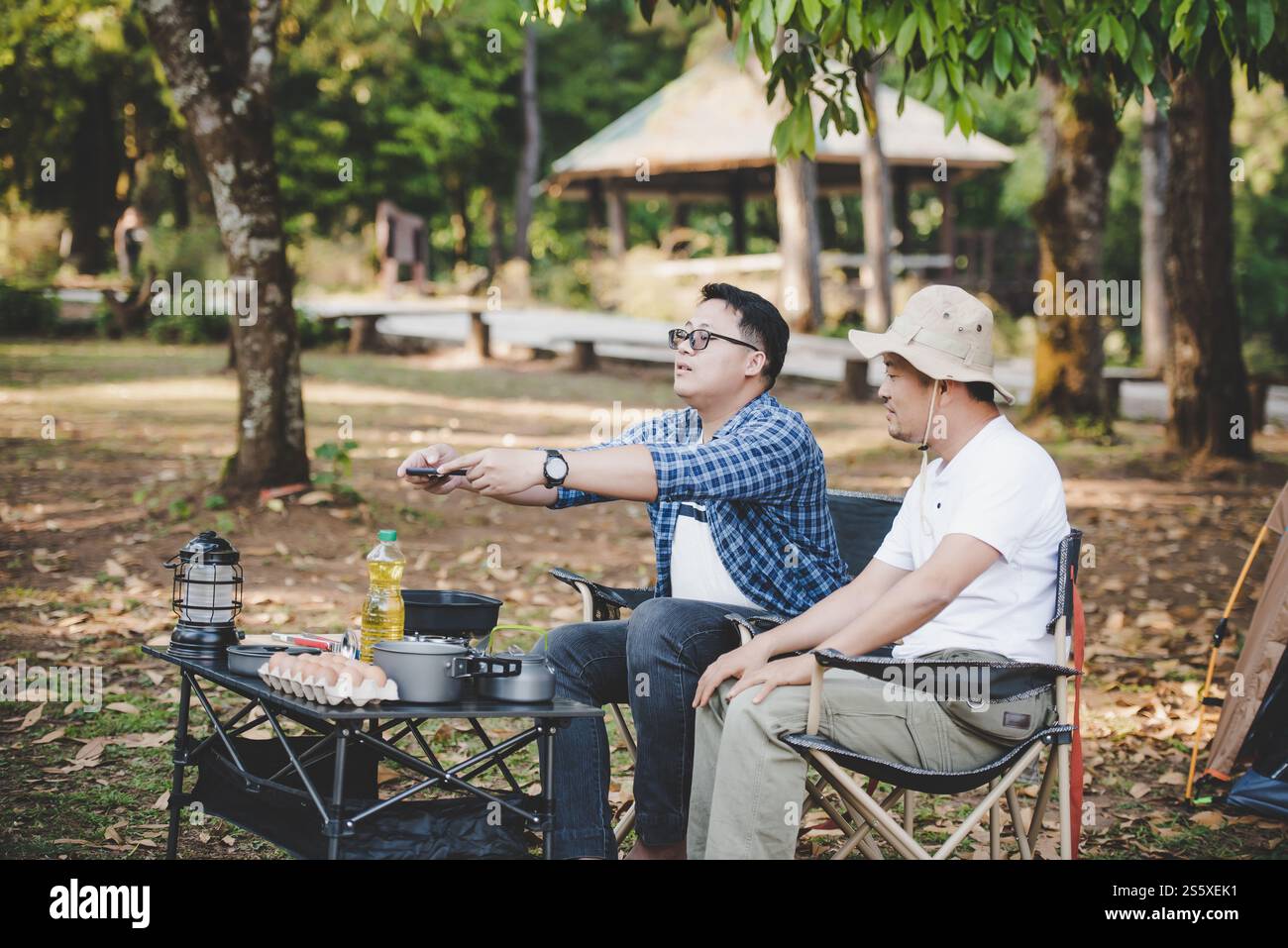 Ritratto di uomini viaggiatori asiatici che scattano una foto su smartphone in campeggio. Cucina all'aperto, viaggi, campeggio, stile di vita. Foto Stock