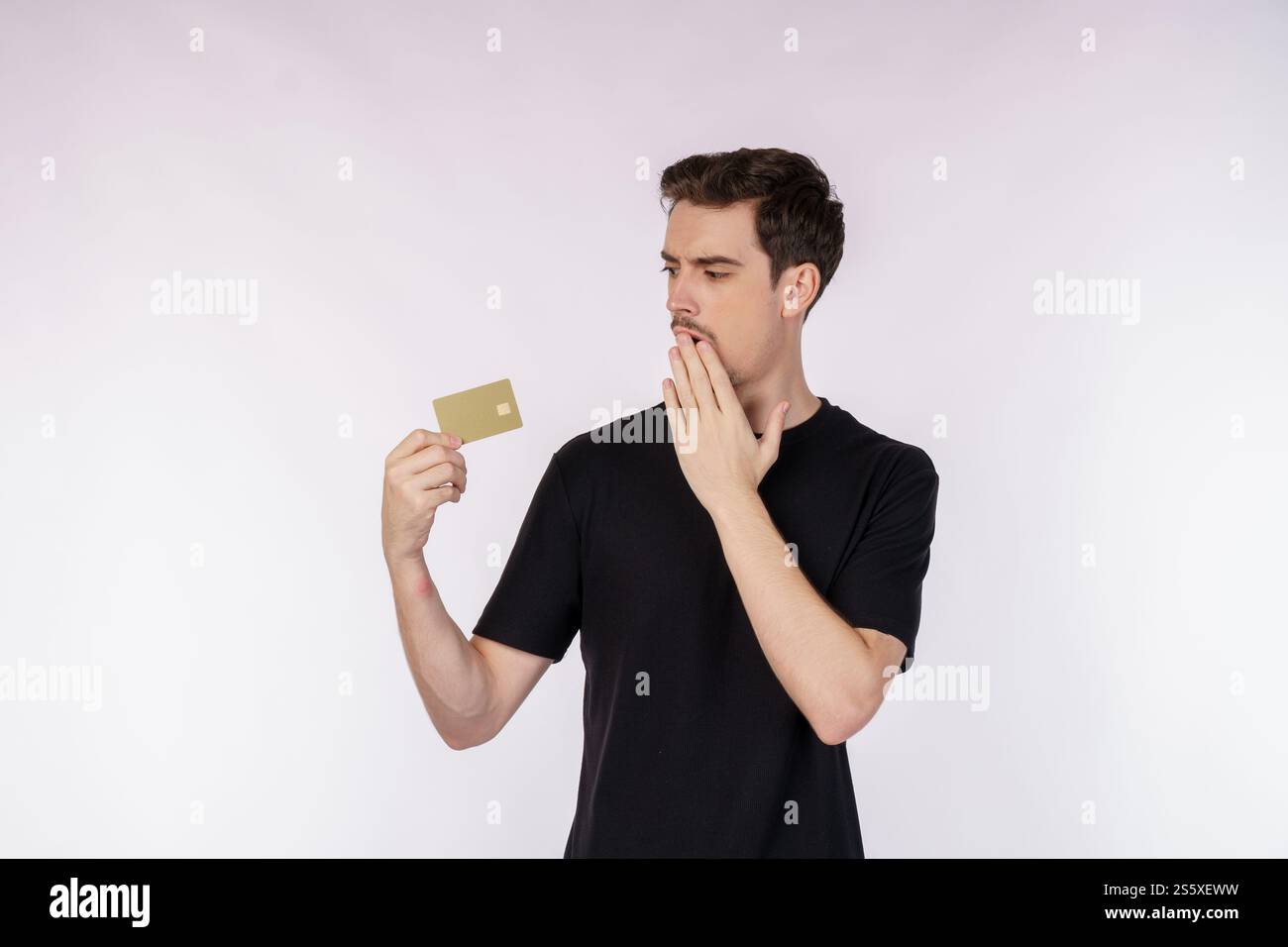 Ritratto dell'uomo sorpreso in abiti casual che mostra la carta di credito isolata su sfondo bianco. Shopping online, e-commerce, Internet banking, Foto Stock