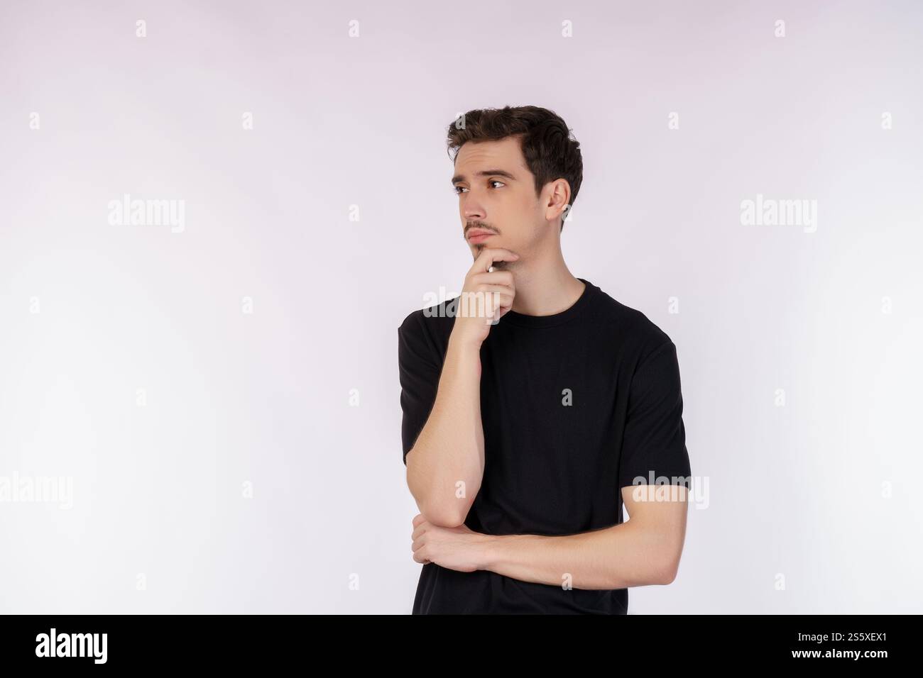 Ritratto di un giovane che pensa toccando il mento isolato su sfondo bianco. Pensare preoccupato per una domanda, preoccupato e nervoso con la mano sopra Foto Stock