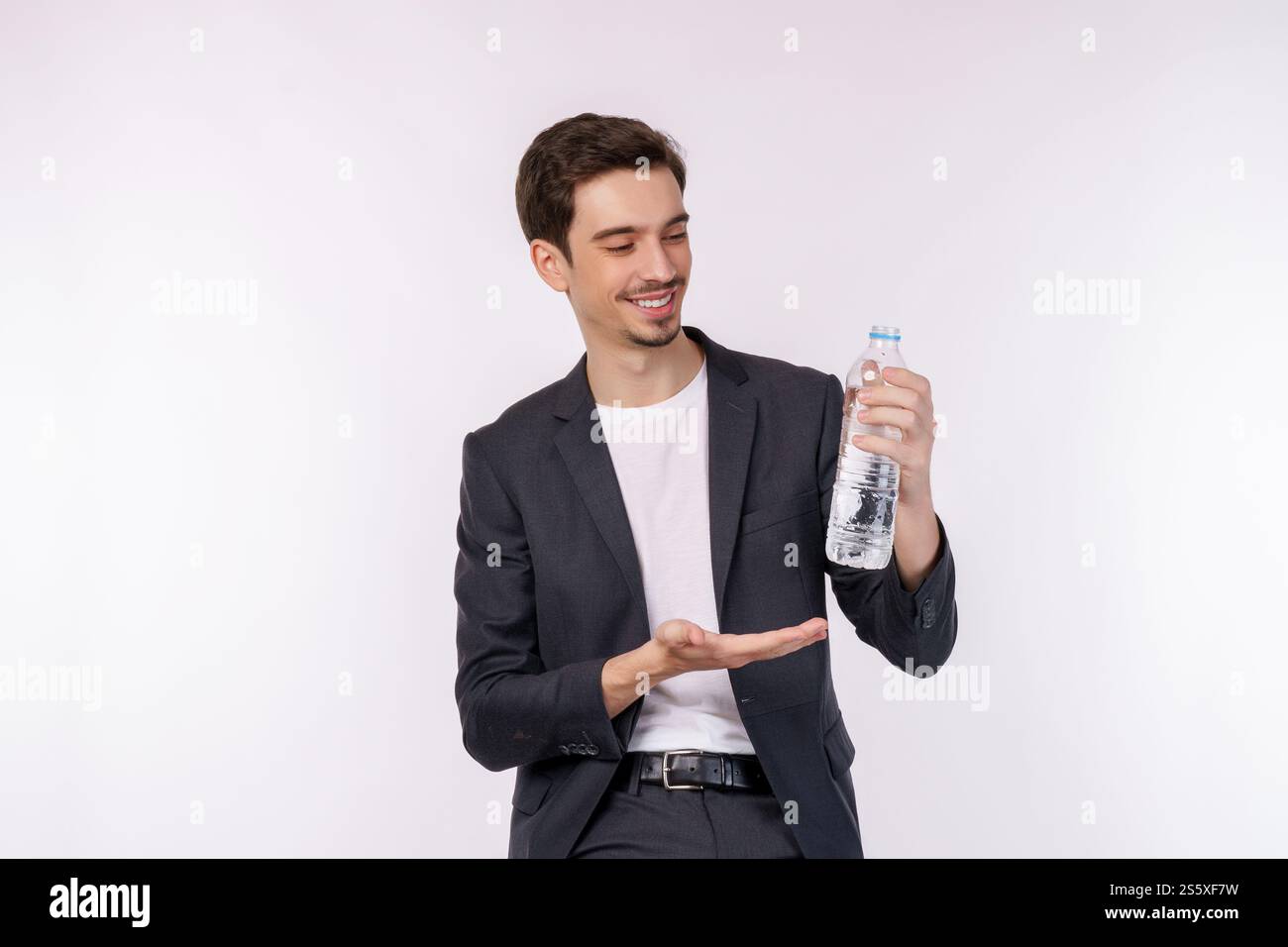 Ritratto di un giovane felice che mostra l'acqua in una bottiglia isolata su sfondo bianco. Alimentazione sana, dieta e concetto di persone. Foto Stock