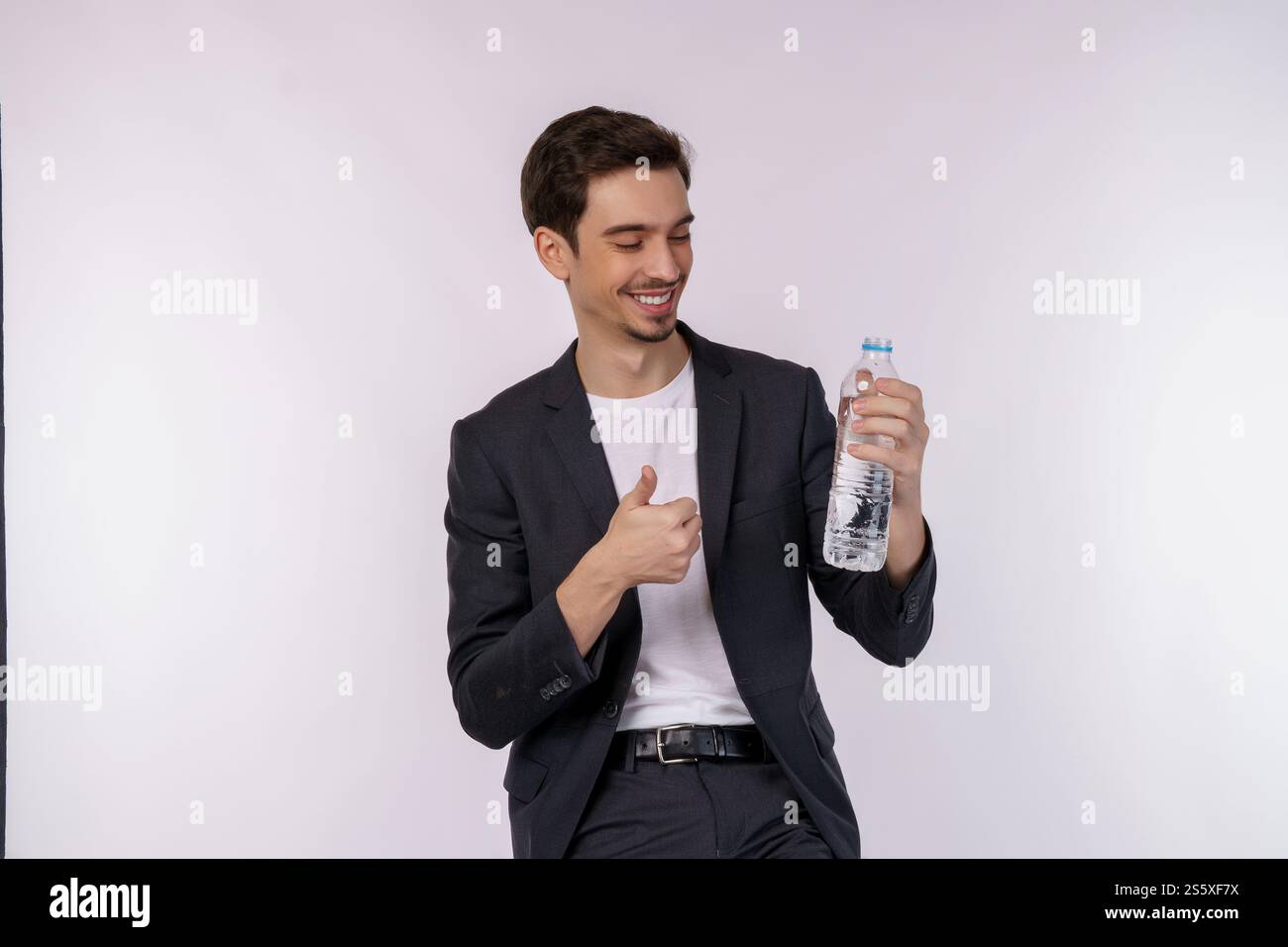 Ritratto di un giovane felice che mostra l'acqua in una bottiglia isolata su sfondo bianco. Alimentazione sana, dieta e concetto di persone. Foto Stock