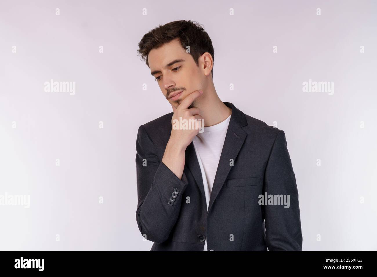 Ritratto di un giovane uomo d'affari che pensa di toccare il mento isolato su sfondo bianco. Pensare preoccupato per una domanda, preoccupato e nervoso Foto Stock