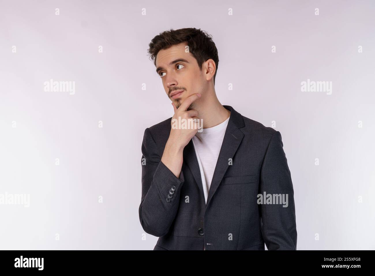 Ritratto di un giovane uomo d'affari che pensa di toccare il mento isolato su sfondo bianco. Pensare preoccupato per una domanda, preoccupato e nervoso Foto Stock