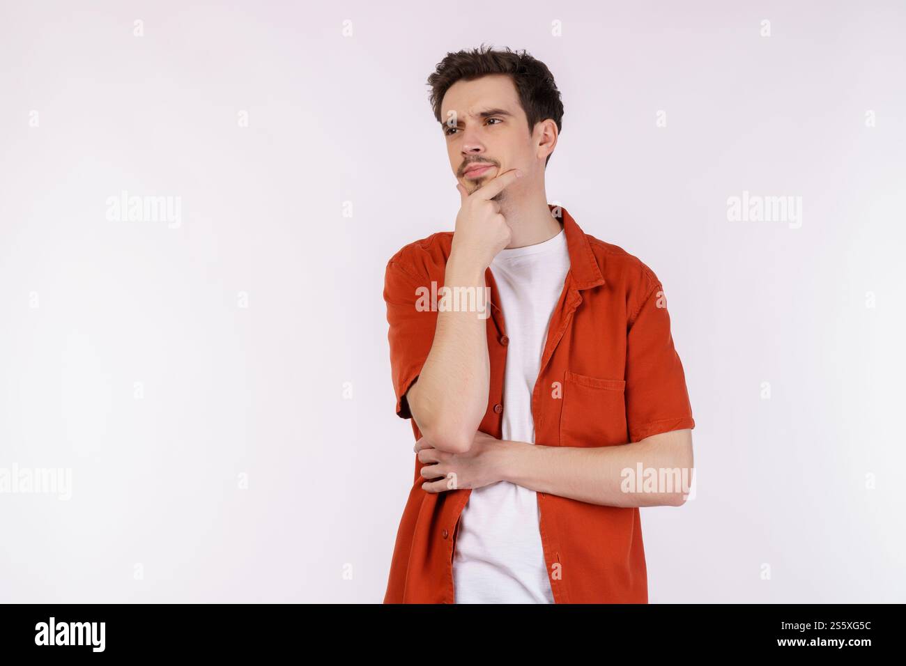 Ritratto di un giovane che pensa toccando il mento isolato su sfondo bianco. Pensare preoccupato per una domanda, preoccupato e nervoso con la mano sopra Foto Stock