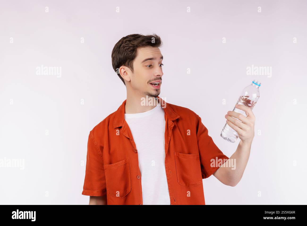 Ritratto di un giovane felice che mostra l'acqua in una bottiglia isolata su sfondo bianco. Alimentazione sana, dieta e concetto di persone. Foto Stock