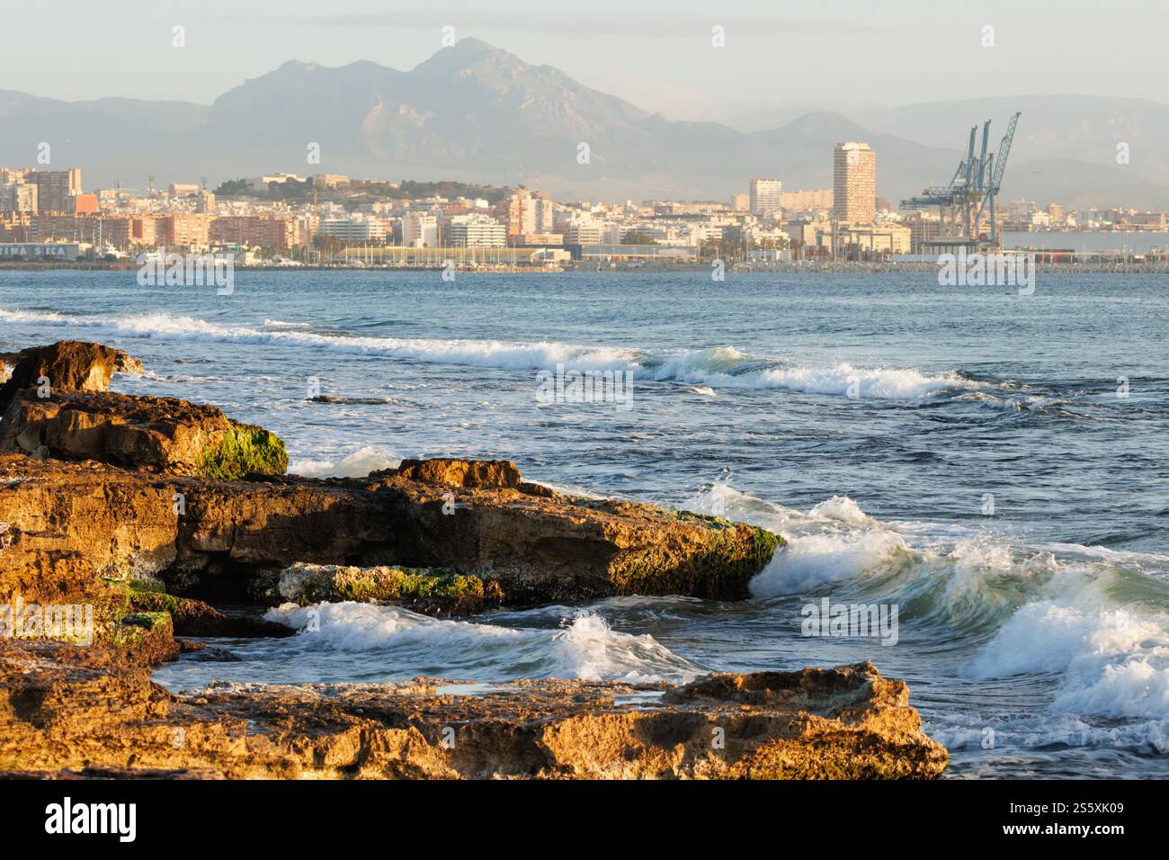 Vista sul mare con la città di Alicante sullo sfondo dalla spiaggia di Agua Amarga, Spagna Foto Stock