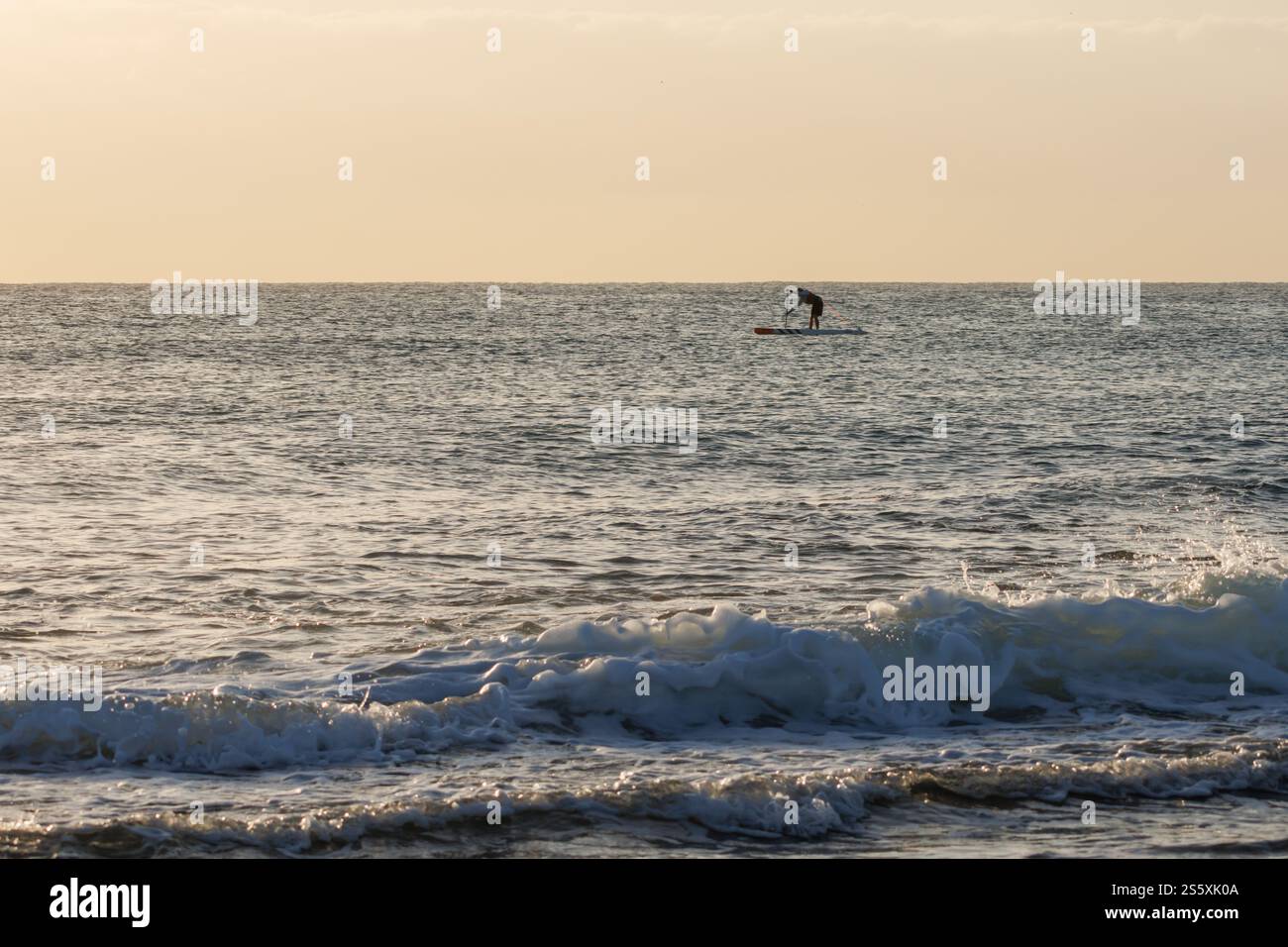 Silhouette di una persona irriconoscibile che pratica paddle surf all'alba sulla spiaggia di Agua Amarga ad Alicante, Spagna Foto Stock