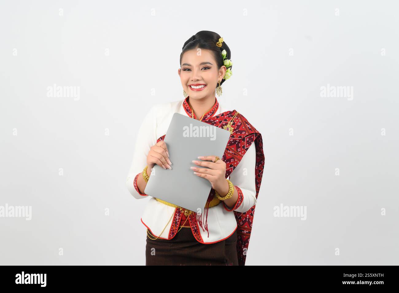 Ritratto di una giovane donna in abbigliamento tradizionale tailandese del nord-est con computer portatile, bella donna asiatica in bel vestito che regge un notebook mock-up Foto Stock
