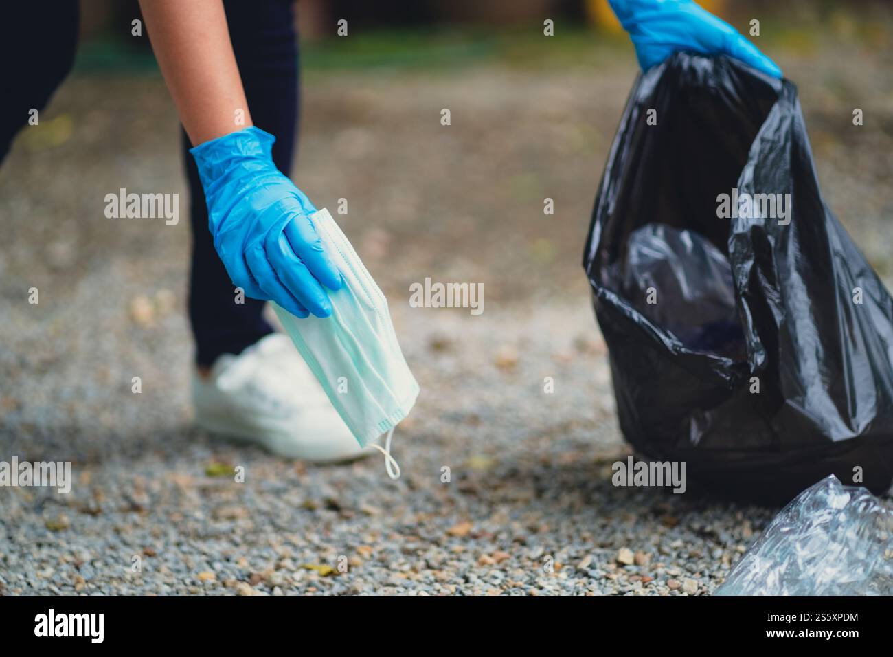 Donna volontaria di beneficenza che tiene la maschera chirurgica protettiva durante la pandemia di coronavirus. COVID-19. gettare via la maschera protettiva usata in Foto Stock