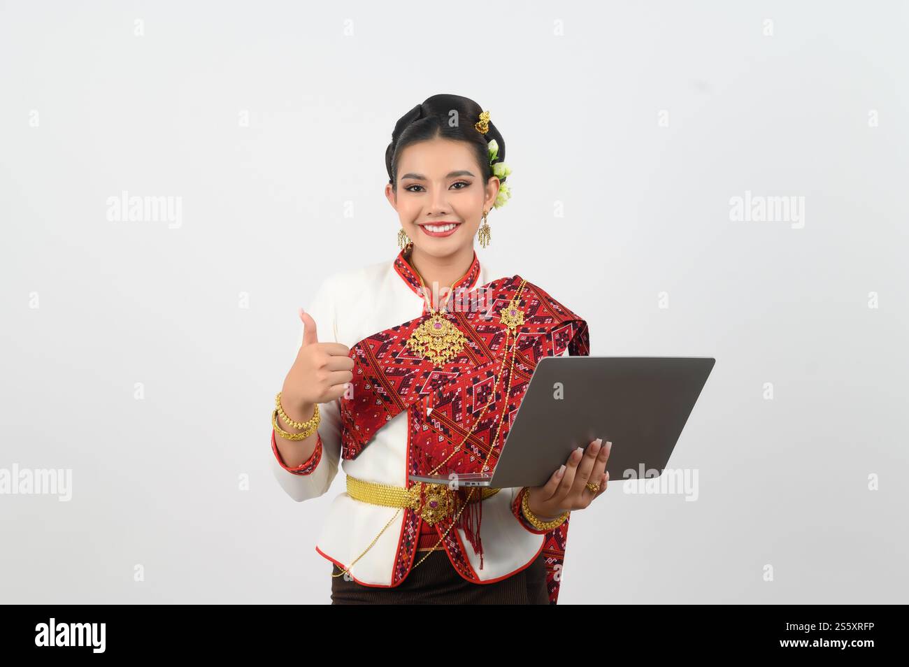 Ritratto di una bella donna in abbigliamento tradizionale tailandese del nord con computer portatile, bella donna asiatica in abito tailandese Lanna pollice su e tenendo in mano Foto Stock