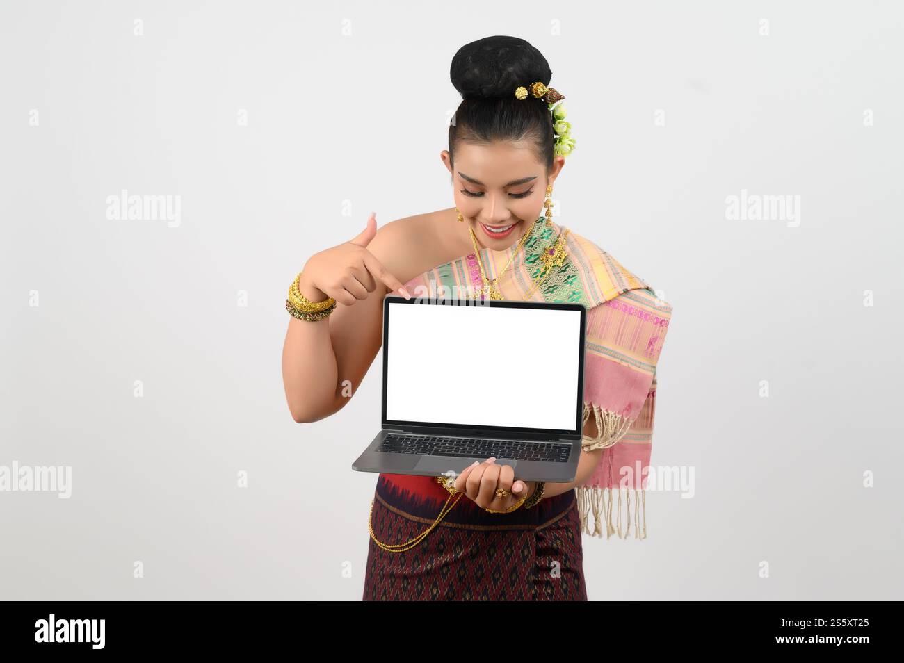 Ritratto di una giovane donna in abbigliamento tradizionale tailandese del nord-est con computer portatile, bella donna asiatica in bel vestito che regge un notebook mock-up Foto Stock