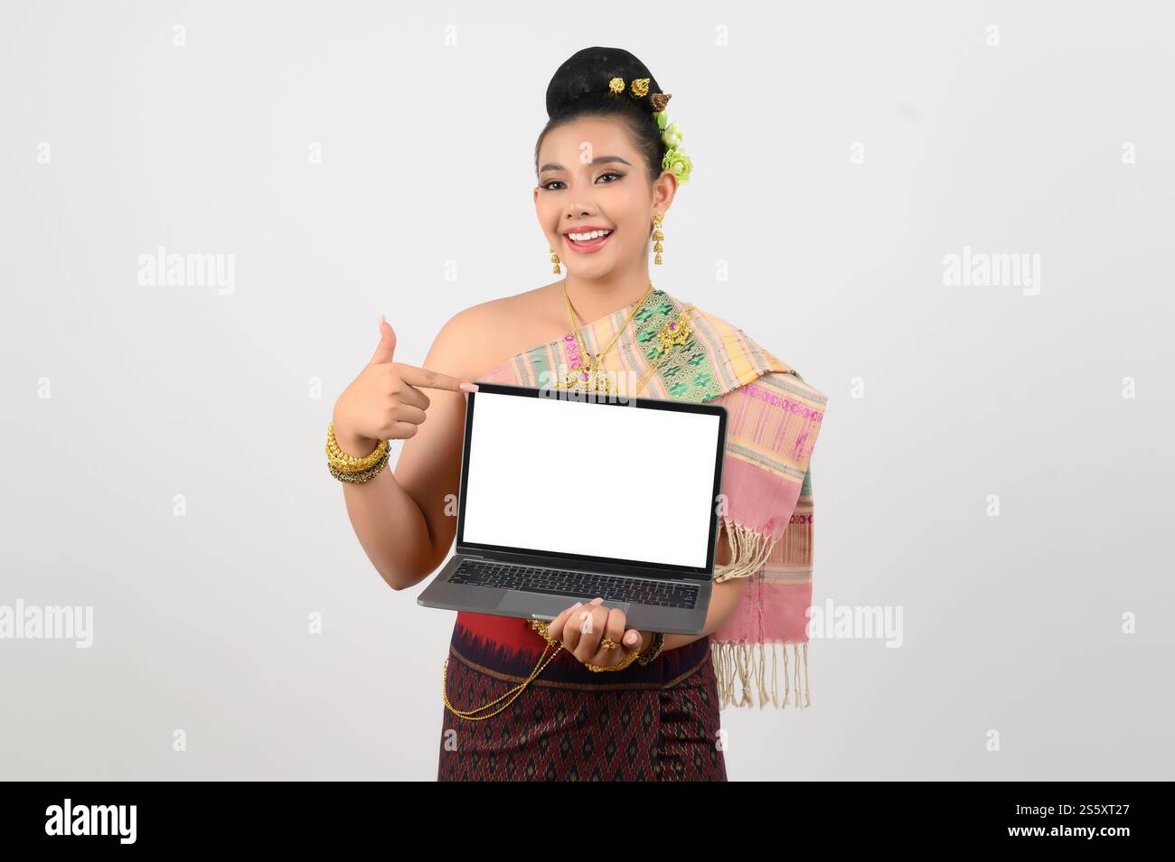Ritratto di una giovane donna in abbigliamento tradizionale tailandese del nord-est con computer portatile, bella donna asiatica in bel vestito che regge un notebook mock-up Foto Stock