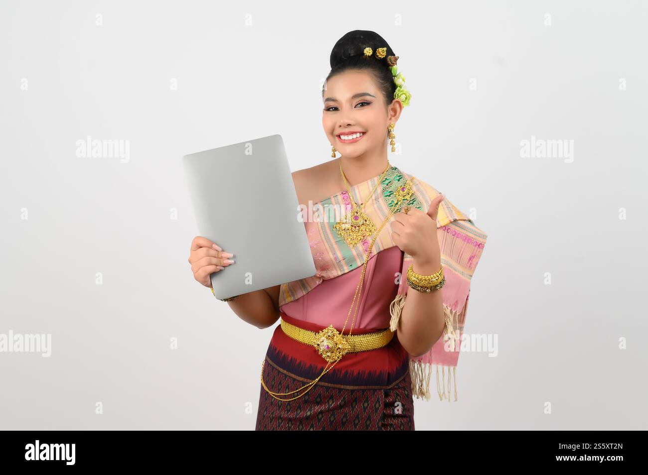 Ritratto di una giovane donna in abbigliamento tradizionale tailandese del nord-est che tiene in mano un computer portatile, bella donna asiatica in bel vestito bianco Foto Stock
