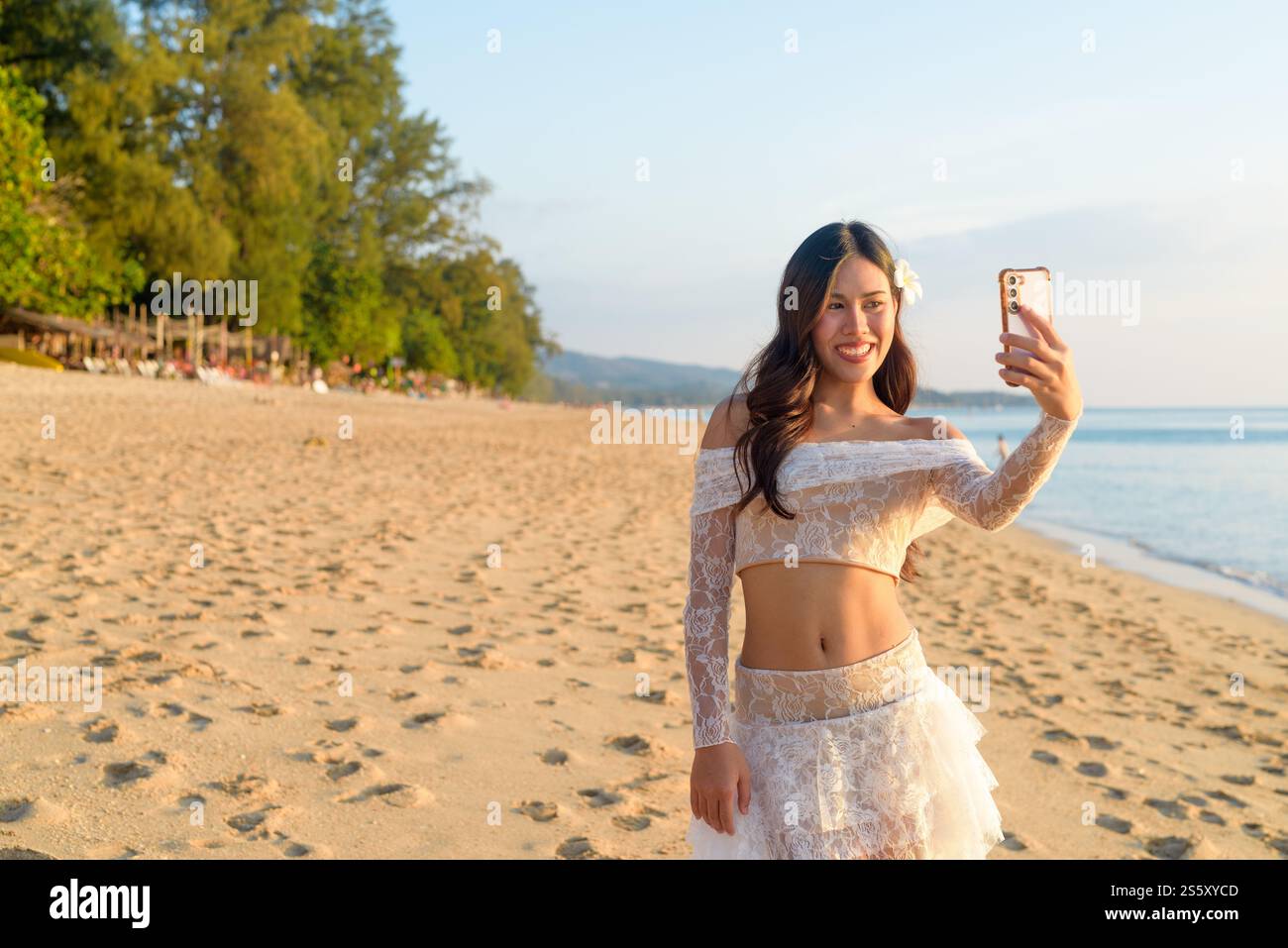Influencer Lifestyle Woman Creating Content on Tropical Beach at Dusk Concept Foto Stock