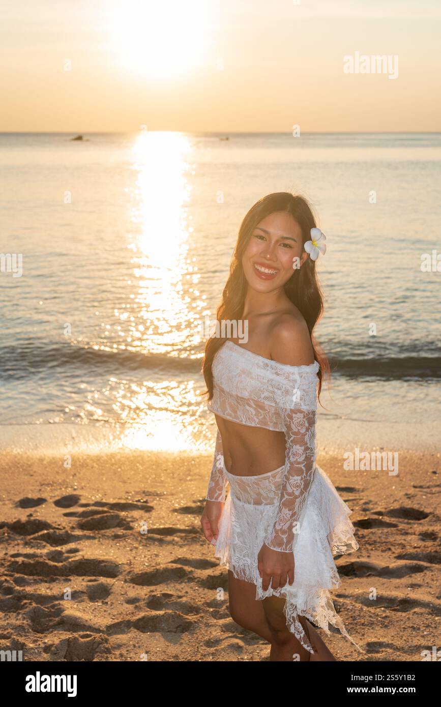 Bella giovane donna thailandese felice alla spiaggia tropicale durante il tramonto Foto Stock