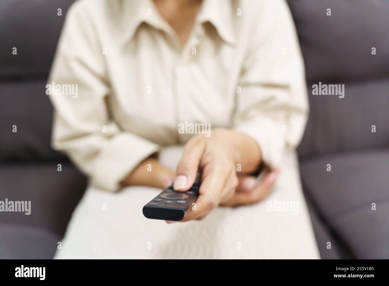 Donna anziana che guarda la smart TV e usa il telecomando che tiene la mano la televisione telecomando audio la donna asiatica di mezza età la televisione di film Foto Stock