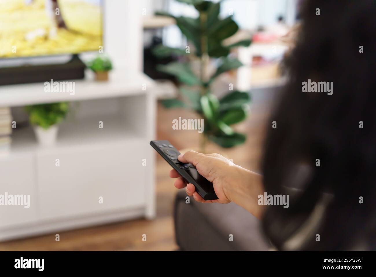 Donna anziana che guarda la smart TV e usa il telecomando che tiene la mano la televisione telecomando audio la donna asiatica di mezza età la televisione di film Foto Stock