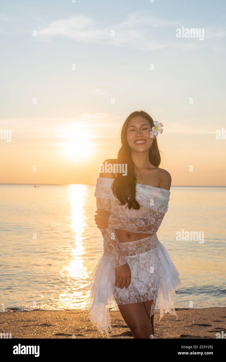 Bella giovane donna thailandese felice alla spiaggia tropicale durante il tramonto Foto Stock