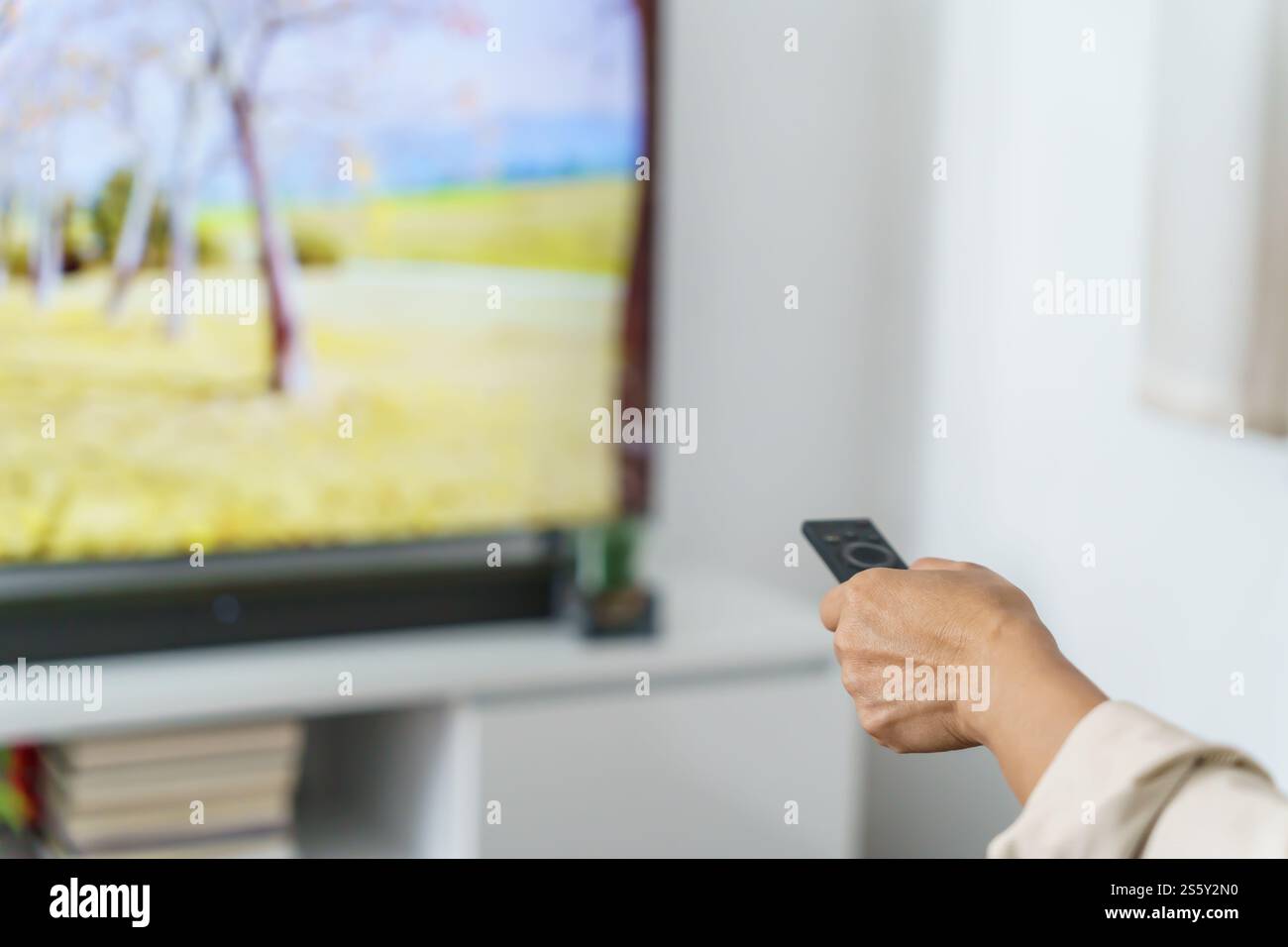Donna anziana che guarda la smart TV e usa il telecomando che tiene la mano la televisione telecomando audio la donna asiatica di mezza età la televisione di film Foto Stock