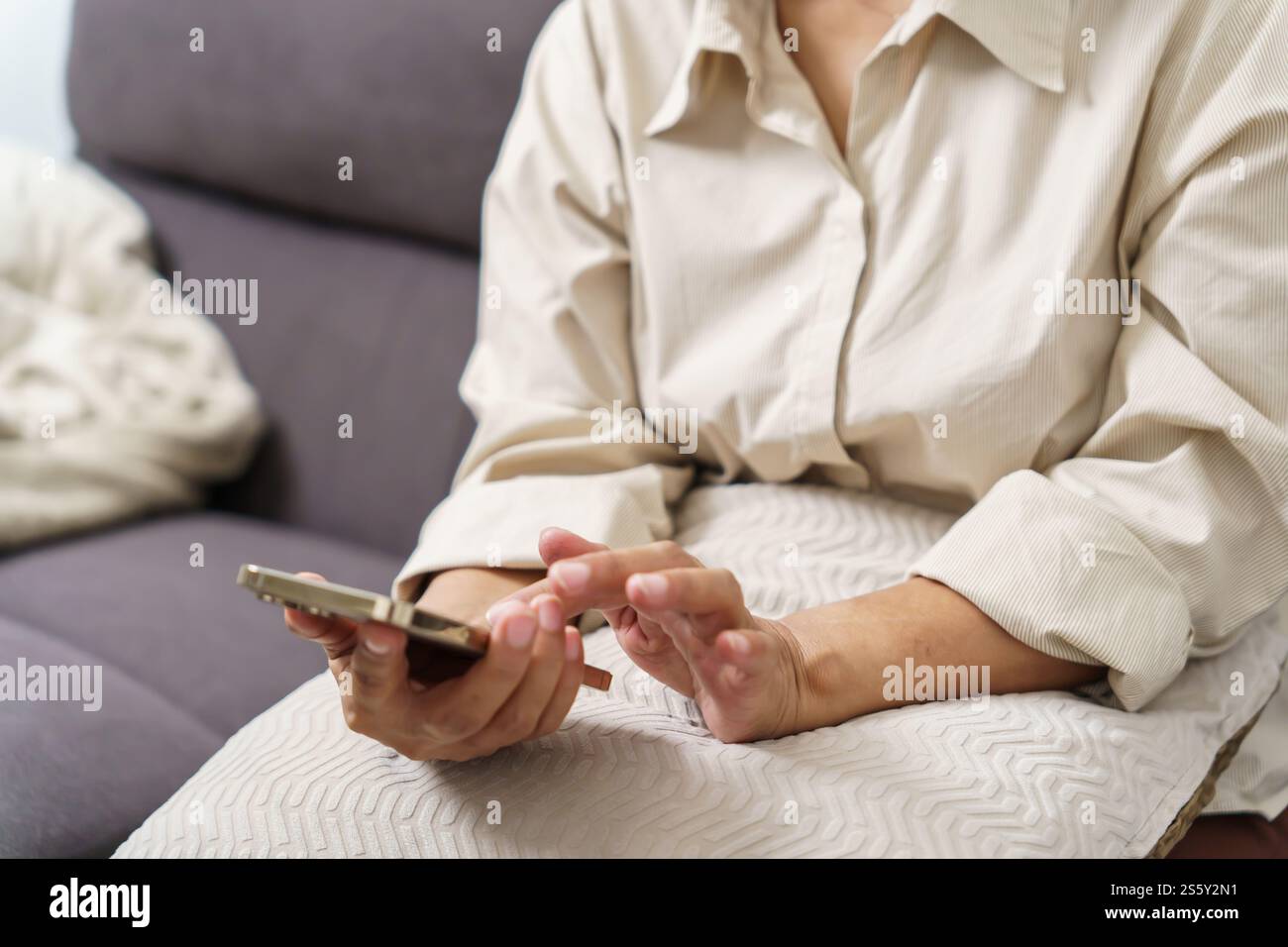 Donna asiatica di mezza età che tiene il telefono cellulare. donna anziana con smartphone. donna anziana che utilizza lo smartphone a casa con il concetto di tecnologia. Foto Stock