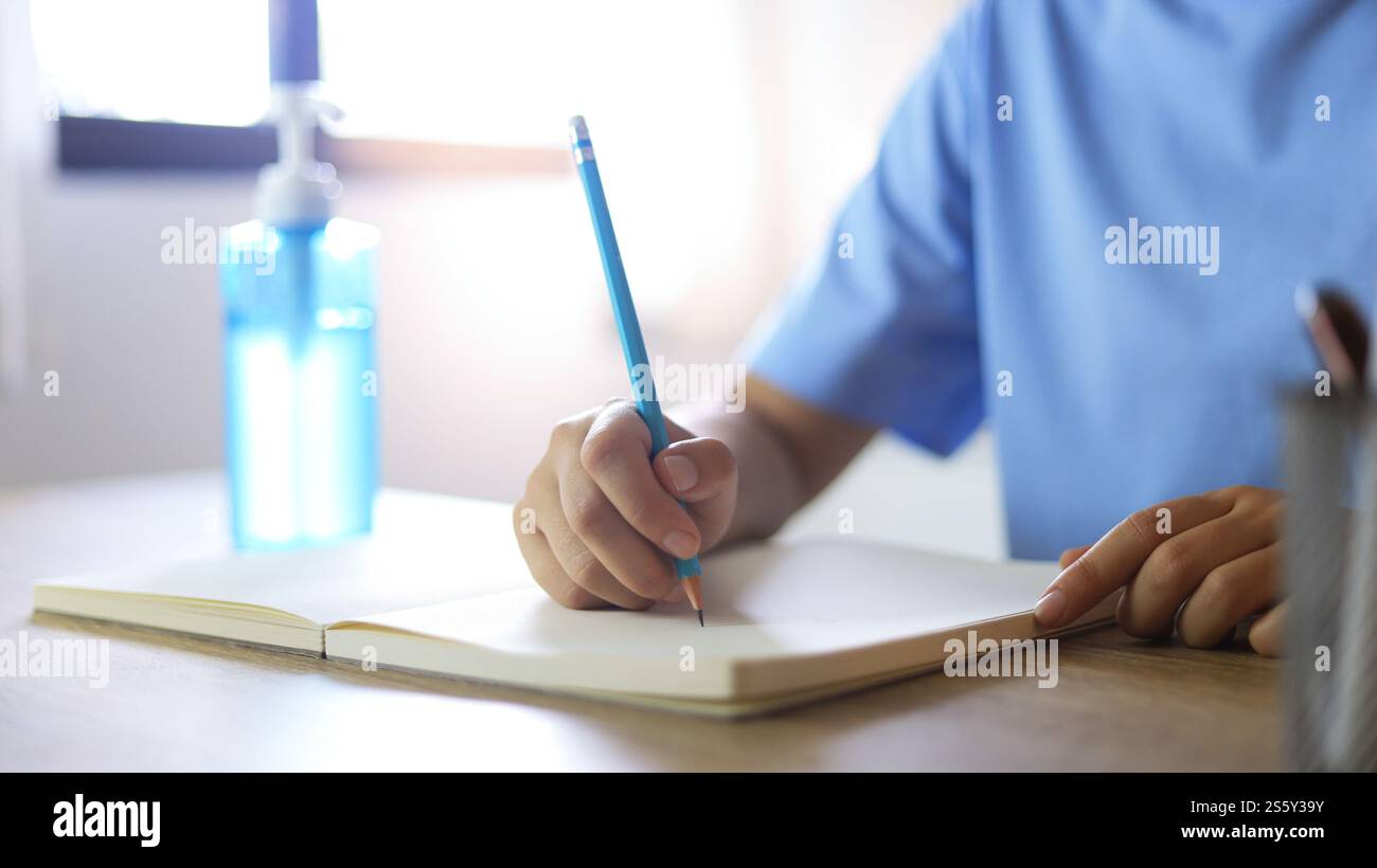 Giovane donna asiatica che indossa maschera facciale medica fatta a mano che lavora da sola distanziando politica con. Gel igienizzante per le mani durante il coronavirus o il virus covid-19 Foto Stock