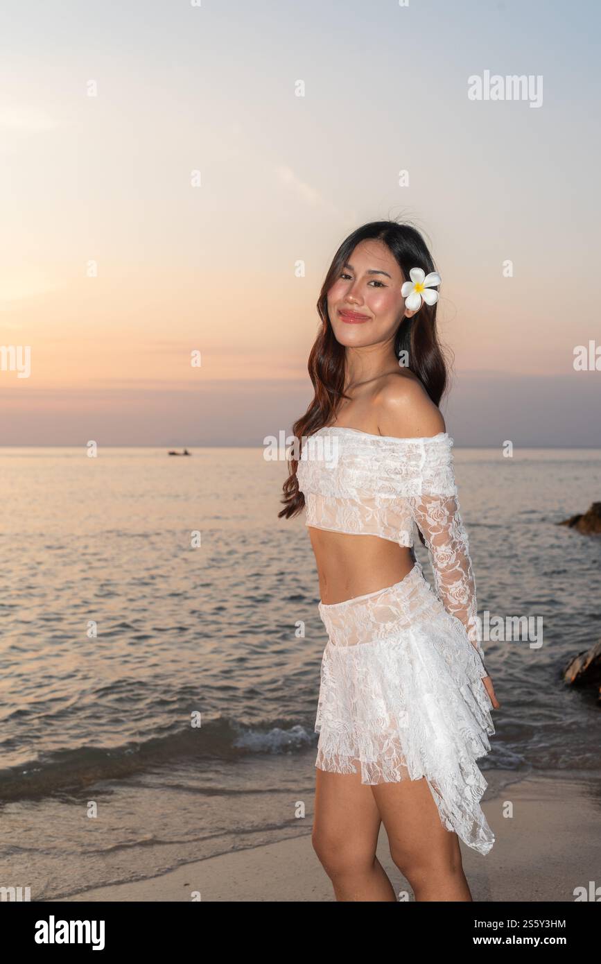 Bella giovane donna thailandese felice alla spiaggia tropicale durante il tramonto Foto Stock
