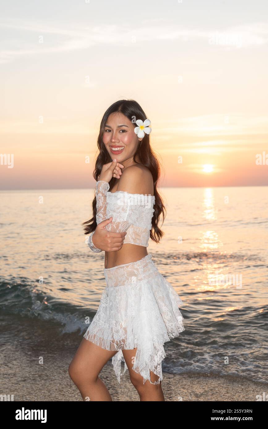 Bella giovane donna thailandese felice alla spiaggia tropicale durante il tramonto Foto Stock