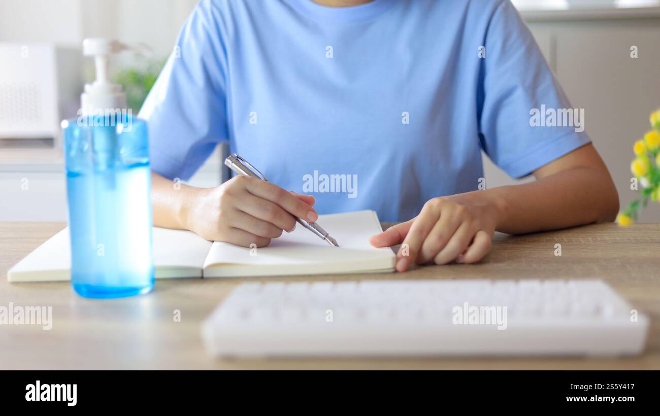 Giovane donna asiatica che indossa maschera facciale medica fatta a mano che lavora da sola distanziando politica con. Gel igienizzante per le mani durante il coronavirus o il virus covid-19 Foto Stock