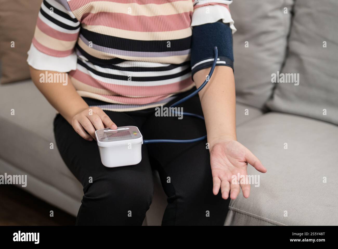 Controllo automatico della pressione sanguigna e della frequenza cardiaca da parte della donna in sovrappeso Plus size. Foto Stock