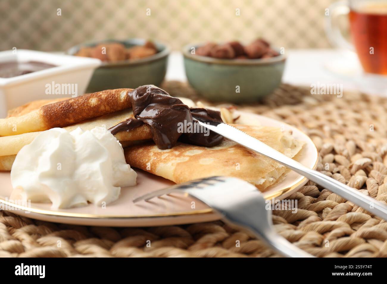 Deliziose crepe con pasta di cioccolato e panna montata sul tavolo, primo piano Foto Stock