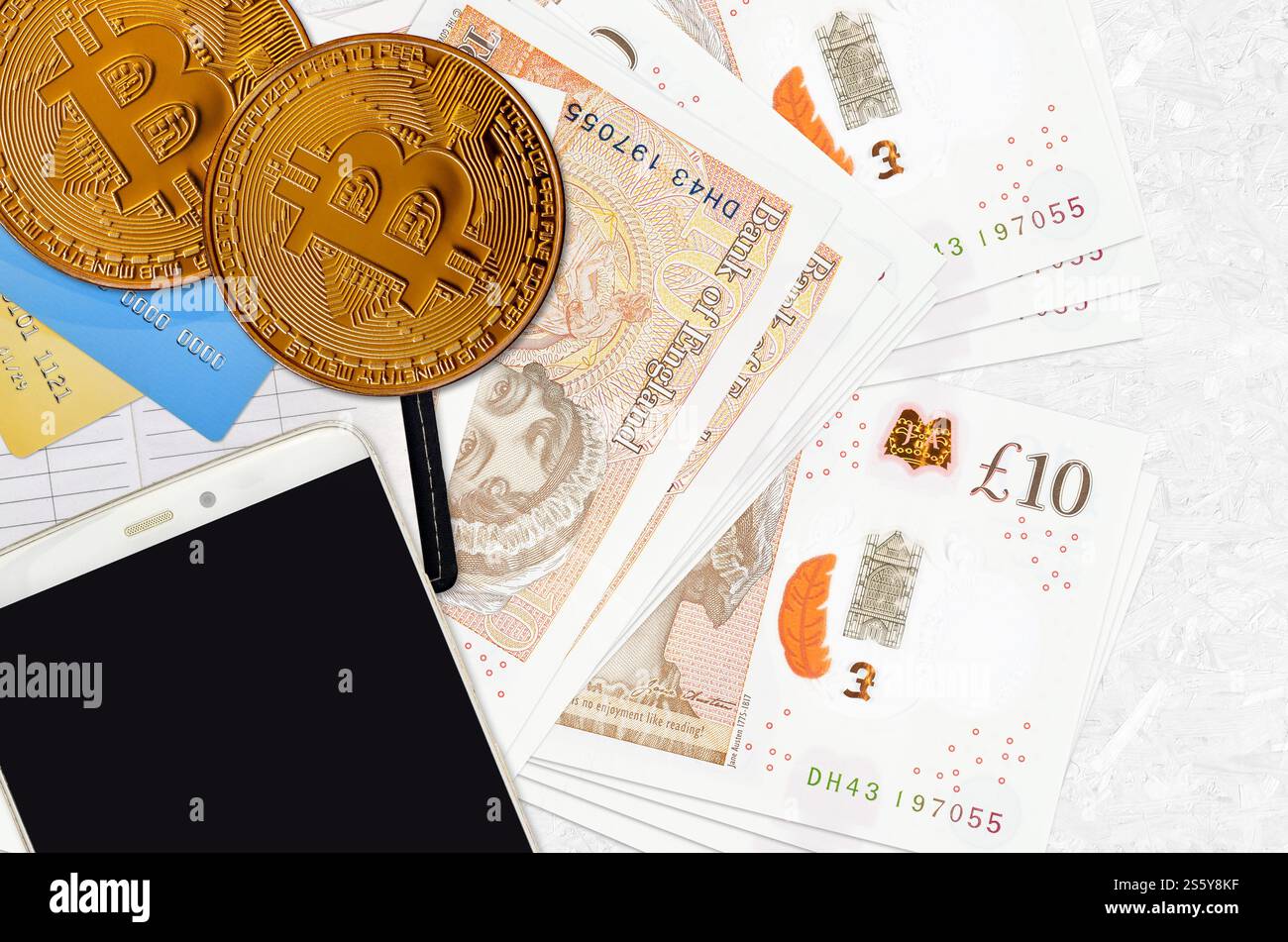 Banconote da 10 sterline britanniche e bitcoin dorati con smartphone e carte di credito. Concetto di investimento in criptovaluta. Crypto mining o trading Foto Stock
