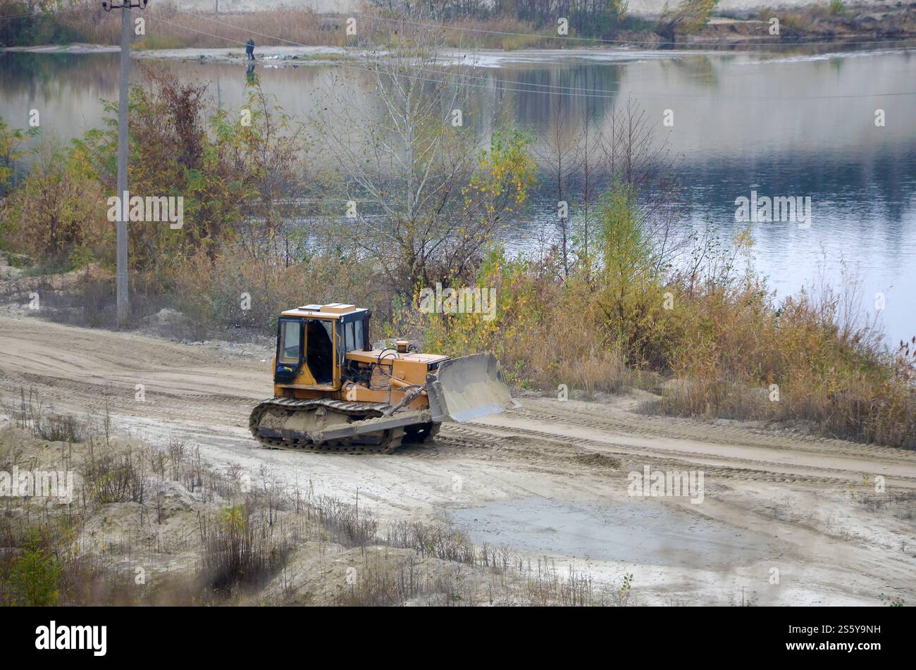 Aggregato da cava con macchinari per impieghi gravosi nel settore delle costruzioni. Escavatore pala Caterpillar con retroescavatore per la cava del cantiere. Foto Stock