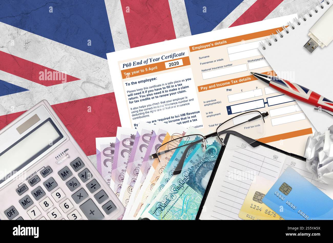 Modulo fiscale inglese P60 certificato di fine anno da HM Revenue and Customs si trova sul tavolo con gli articoli per ufficio. Documentazione HMRC e processo di pagamento delle imposte in Foto Stock