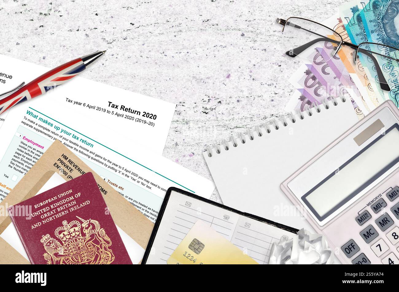 Il modulo inglese sa100 dichiarazione dei redditi di HM e dogana si trova sul tavolo con gli articoli per ufficio. Documentazione HMRC e procedura di pagamento delle imposte nel Regno Unito di Foto Stock