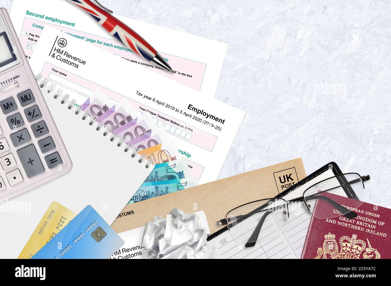 Modulo fiscale inglese sa102 l'impiego da parte di HM revenue and Customs si trova sul tavolo con gli articoli per ufficio. Documentazione HMRC e procedura di pagamento delle imposte nel Regno Unito Foto Stock