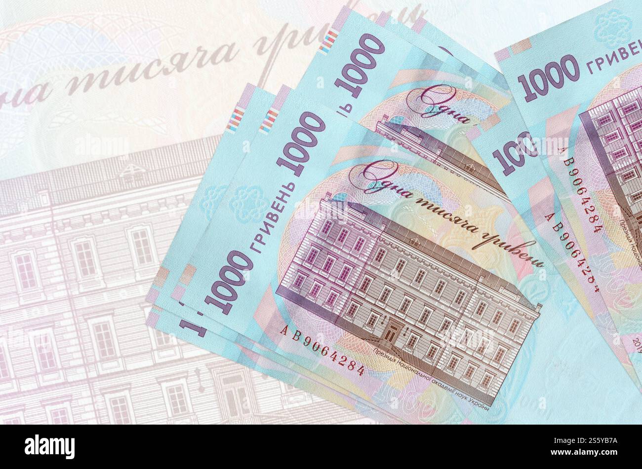 1000 banconote ucraine in hryvnias si trovano in una pila sullo sfondo di una grande banconota semi-trasparente. Presentazione astratta della moneta nazionale. Affari Foto Stock