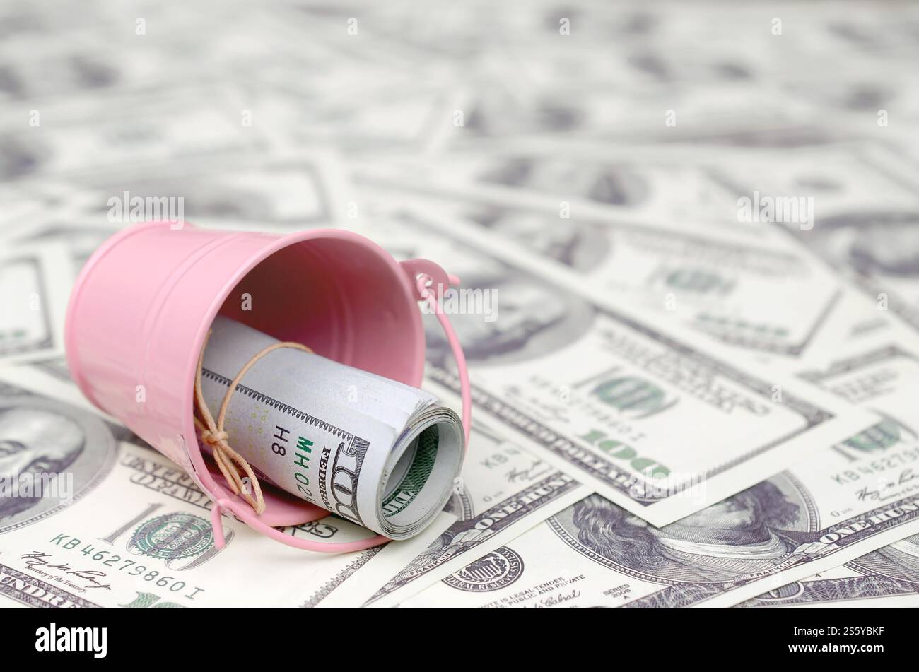 Un pacchetto di dollari USA in un secchio di metallo rosa su una serie di banconote da un dollaro. Il concetto di abbondanza e eccesso di denaro. Un pacchetto di dollari USA in un metallo Foto Stock