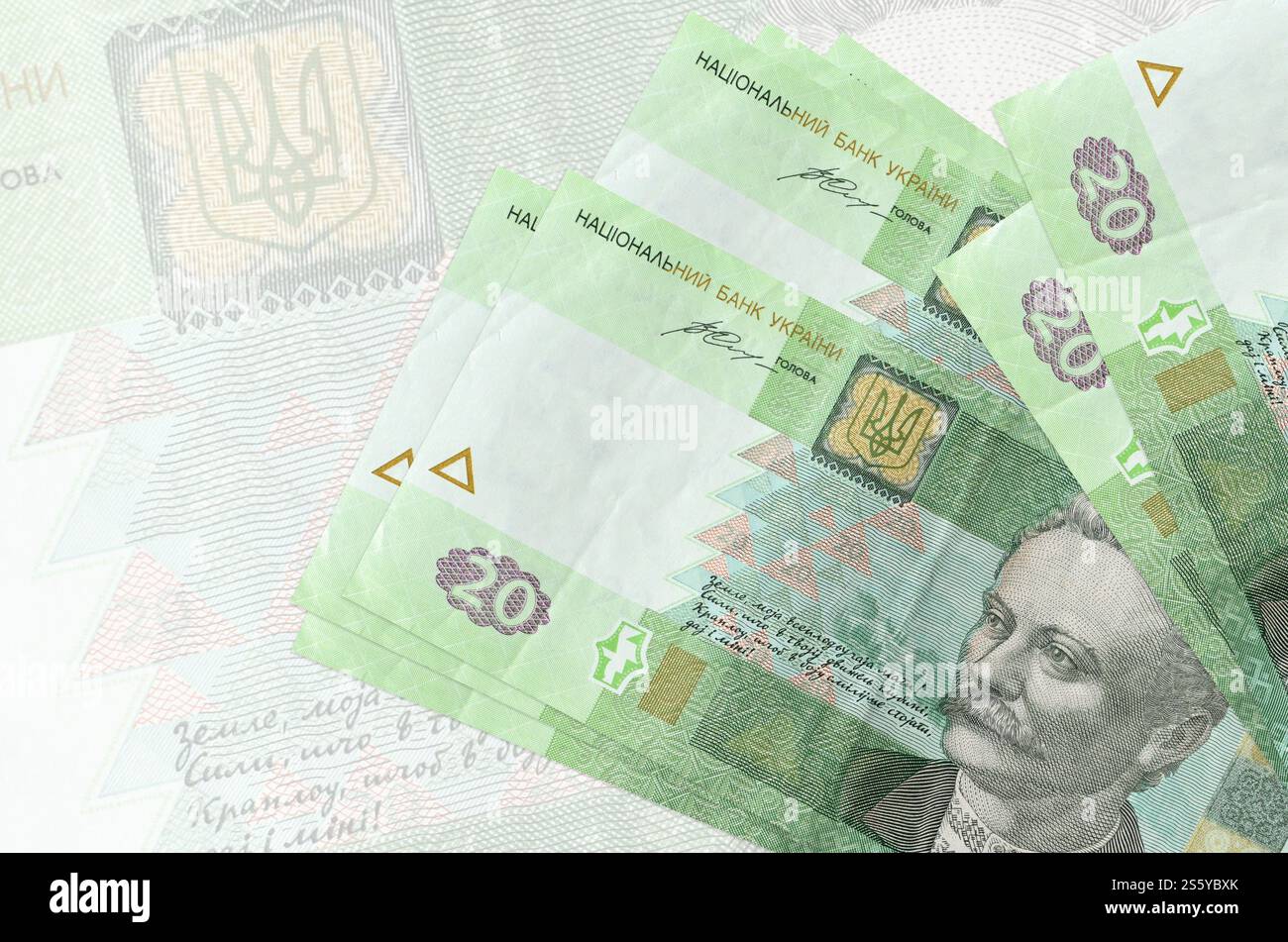 20 banconote ucraine in hryvnias si trovano in una pila sullo sfondo di grandi banconote semitrasparenti. Presentazione astratta della moneta nazionale. Affari Foto Stock