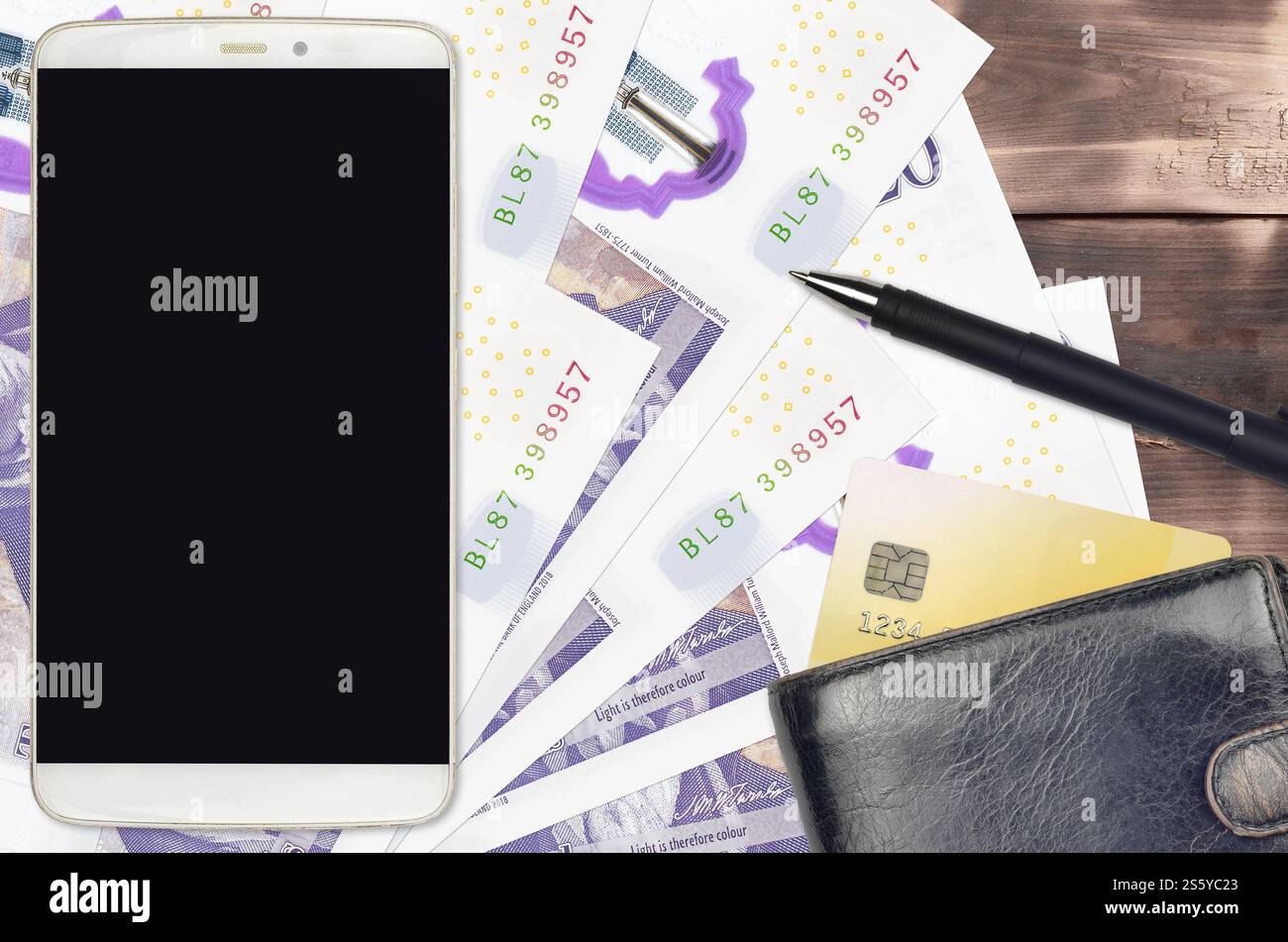 Banconote da 20 sterline britanniche e smartphone con borsetta e carta di credito. Pagamenti elettronici o concetto di e-commerce. Shopping online e business con il portatile Foto Stock