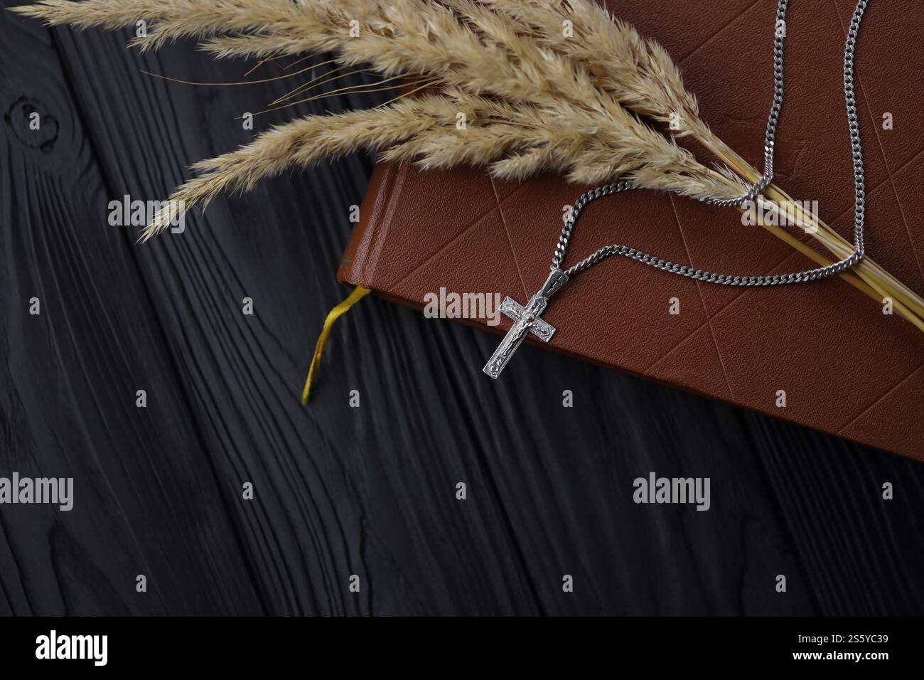 Collana in argento con croce crocifisso su un libro sacro cristiano della bibbia su un tavolo di legno nero. Chiedere benedizioni a Dio con il potere della santità, che Foto Stock