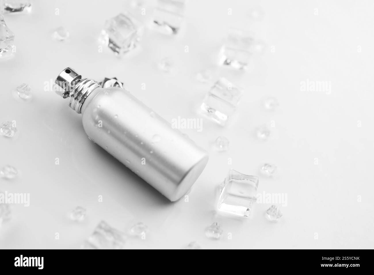 Bottiglia argentata di profumo femminile, Fotografia obiettivo di bottiglia di profumo metallico in cubetti di ghiaccio e acqua su tavola bianca. Vista dall'alto. Prodotto mockup Foto Stock