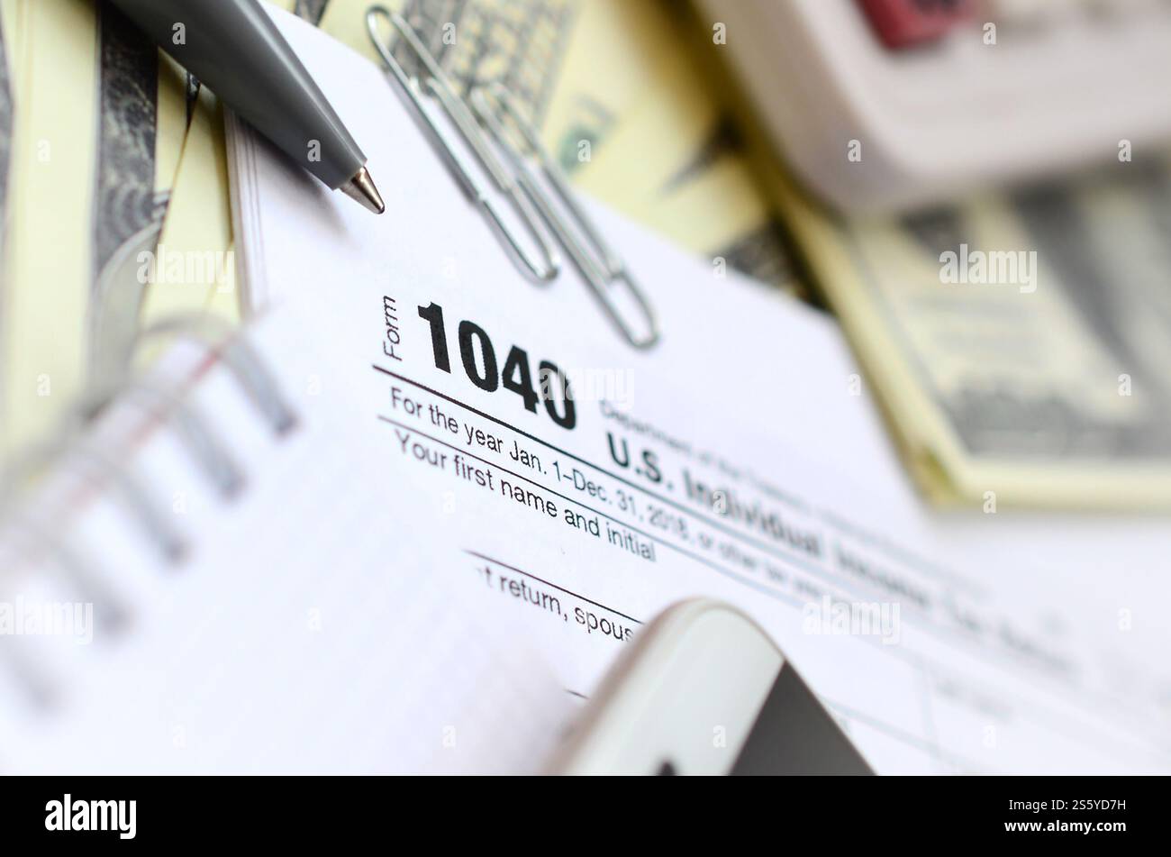 La penna, il notebook, la calcolatrice, lo smartphone e le fatture del dollaro si trova sul modulo di imposta 1040 US Reddito Individuale ritorno di imposta. Il tempo di pagare le tasse Foto Stock