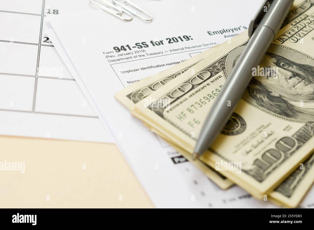 Modulo IRS 941-SS datori di lavoro dichiarazione dei redditi federale trimestrale in bianco si trova con penna e molte banconote da cento dollari sulla pagina del calendario. Concetto del periodo fiscale. Copia Foto Stock