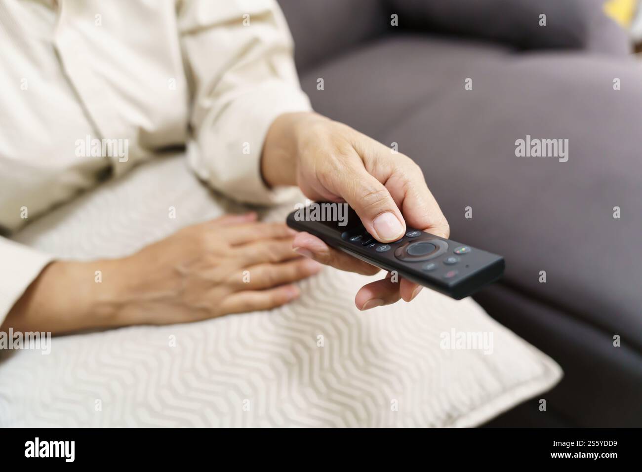 Donna anziana che guarda la smart TV e usa il telecomando che tiene la mano la televisione telecomando audio la donna asiatica di mezza età la televisione di film Foto Stock