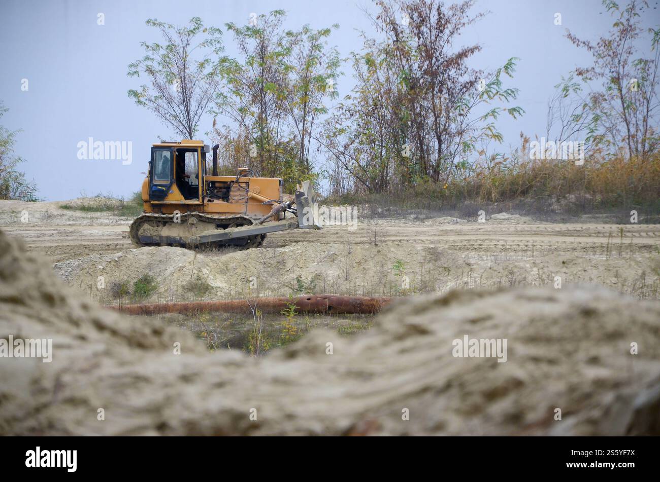 Aggregato da cava con macchinari per impieghi gravosi nel settore delle costruzioni. Escavatore pala Caterpillar con retroescavatore per la cava del cantiere. Foto Stock