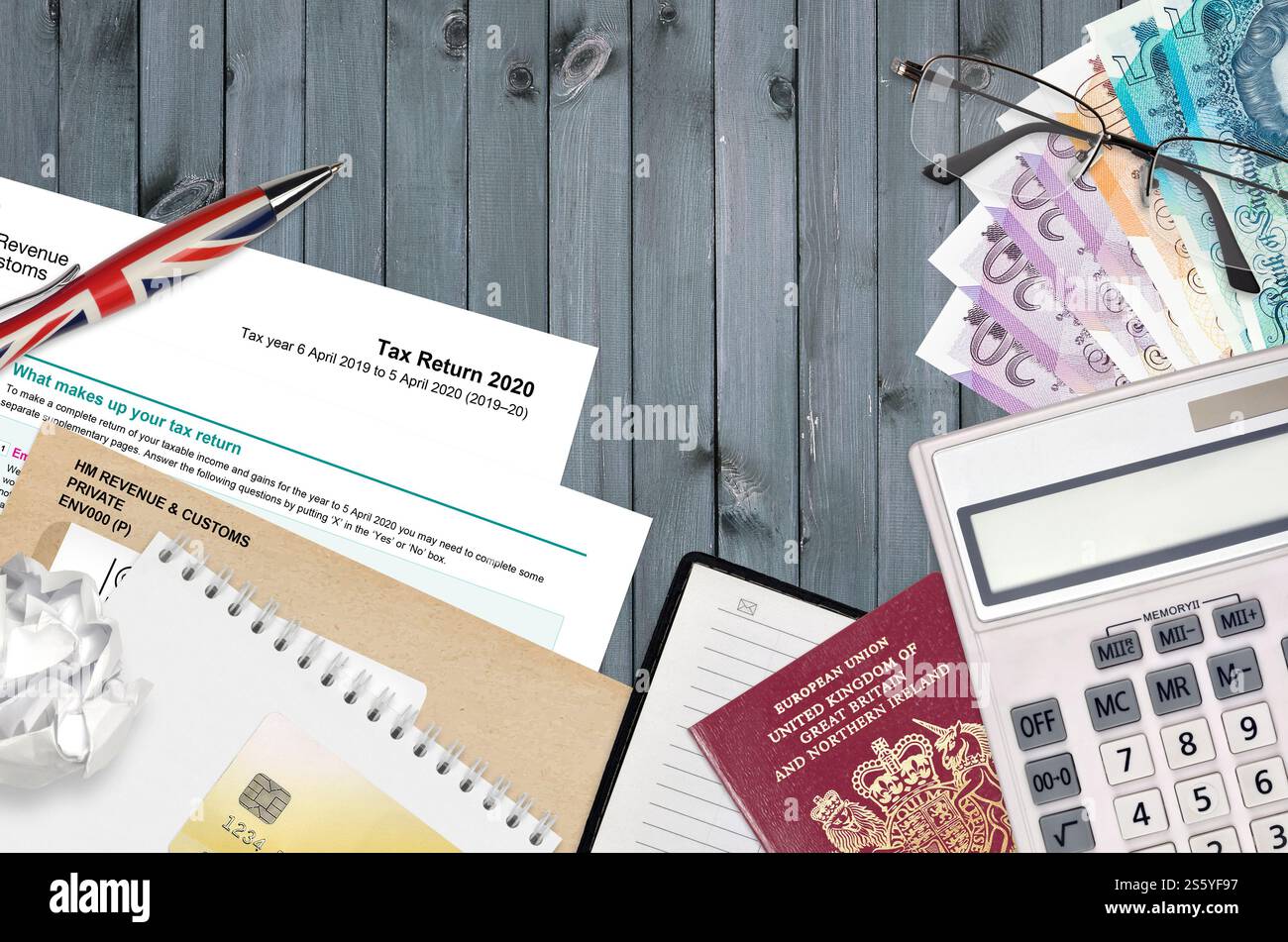 Il modulo inglese sa100 dichiarazione dei redditi di HM e dogana si trova sul tavolo con gli articoli per ufficio. Documentazione HMRC e procedura di pagamento delle imposte nel Regno Unito di Foto Stock