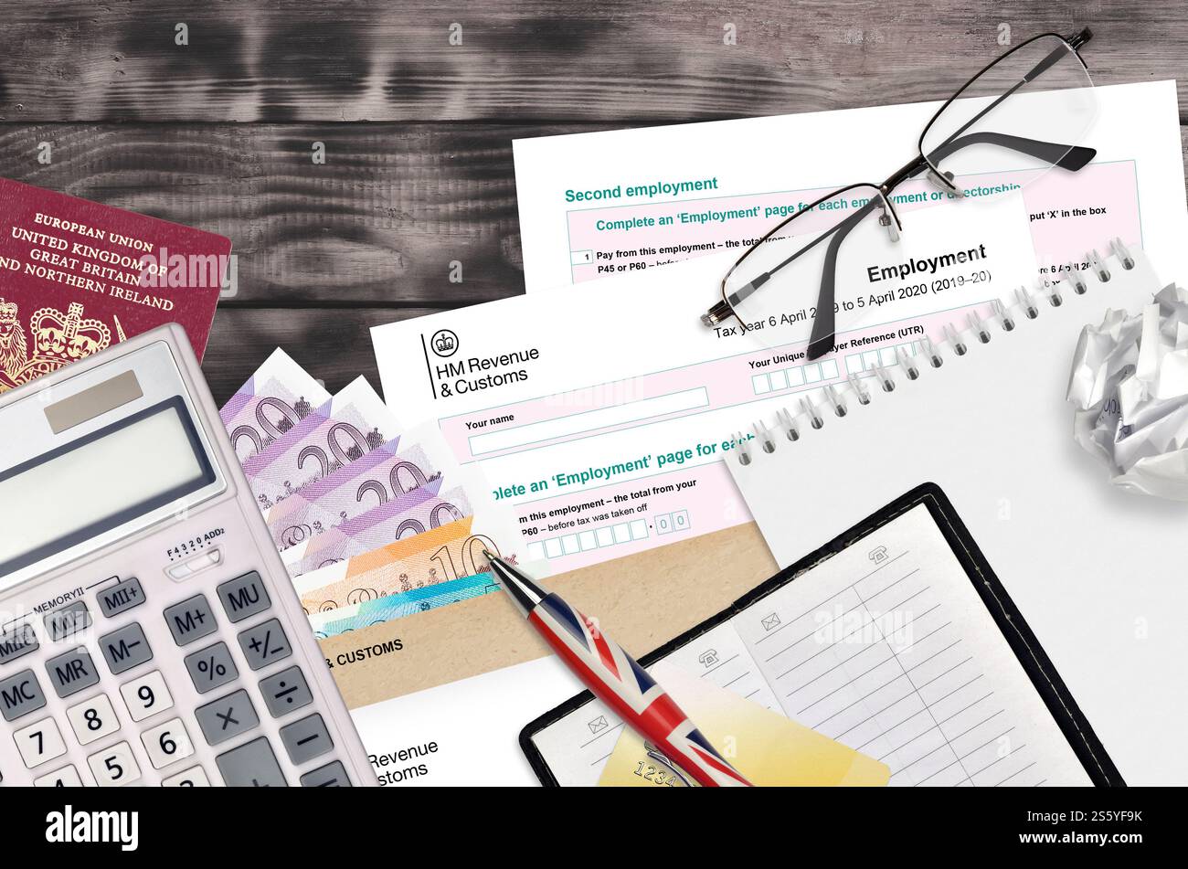 Modulo fiscale inglese sa102 l'impiego da parte di HM revenue and Customs si trova sul tavolo con gli articoli per ufficio. Documentazione HMRC e procedura di pagamento delle imposte nel Regno Unito Foto Stock