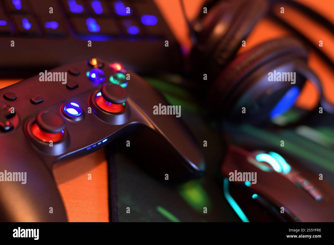 Il moderno gamepad e mouse da gioco è dotato di tastiera e cuffie sul tavolo in primo piano nella scena scura della stanza dei giochi. Dipendenza dai videogiochi tra gli adolescenti Foto Stock