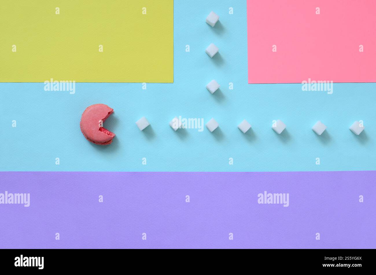 Una composizione di macaroon a bocca aperta che mangia cubetti di zucchero su sfondo pastello blu, rosa, giallo e viola. Il concetto di Foto Stock